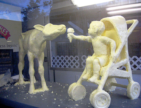 Btter sculpture of boy holding ice cfeaam to cow